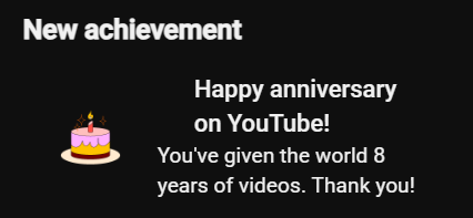 A YouTube notification screen displaying 'New achievement' and 'Happy anniversary on YouTube! You've given the world 8 years of videos. Thank you!' alongside a cake icon.