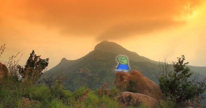 A small Pepe the Frog character is digitally pasted onto a volcanic mountain landscape at sunset. The image serves as a colorful, meme-themed backdrop for a crypto giveaway post referencing $SOL and the token "Raviel," fitting the playful "WAGMI" vibe of the promotion.