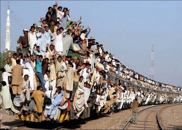 An extremely overpacked train in Pakistan carries dozens of passengers clinging to the roof, sides, and windows, illustrating overwhelming demand. The meme humorously compares this chaotic overcrowding to the sender's flooded direct messages ("My DMs right now").