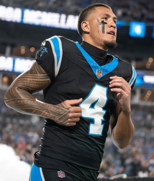Carolina Panthers player wearing number 4 in the team's black uniform, with visible tattoos on his arms, on the football field.