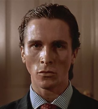 A close-up shot of a sharply dressed man with slicked-back hair in a striped shirt and dark suit, his intense gaze captured mid-expression. The image humorously represents the "Patrick Bateman staring" meme, pairing perfectly with the post's joke about being mesmerized by Solana's rapid 5-minute price charts.