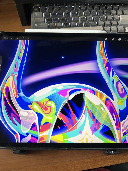 An iPad displaying a vibrant, psychedelic digital artwork featuring colorful swirls, abstract shapes, and a purple arc, positioned in front of a mechanical keyboard.