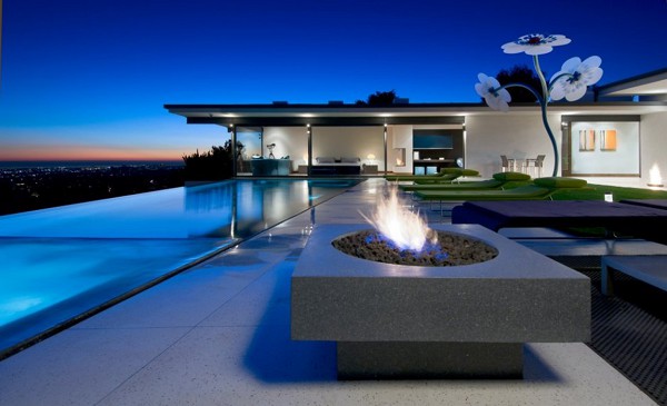 A modern luxury home at dusk features an infinity pool overlooking city lights, with a contemporary fire pit and sculptural flower artwork creating an elegant outdoor entertaining space.

The image's sophisticated architecture and upscale lifestyle aesthetic align with the aspirational "GN active fams" message, while the EthraShip reference may evoke themes of luxury travel or high-end lifestyles that complement the image's premium residential setting.