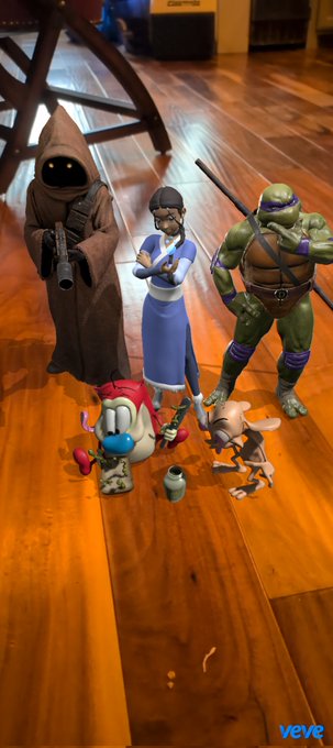 A collection of figurines displayed on a wooden floor including characters resembling a Jawa, a Star Wars Rebels character, Donatello from TMNT, Stimpy from Ren & Stimpy, and a VeVe branded item.