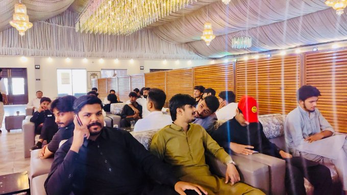 Attendees sit on couches in an ornately decorated hall with chandeliers and draped ceilings during a community gathering in Sangla Hill, Pakistan. The event, hosted by Esha Nadeem for AILYTIS & ODBIT, drew 142 participants to exchange ideas and strengthen local connections.