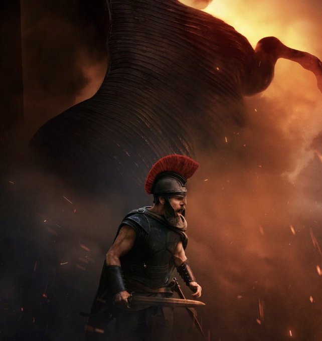 A dramatic digital artwork depicts a Roman-style warrior with a red-plumed helmet wielding a sword beneath a massive dark wing amid fiery embers.