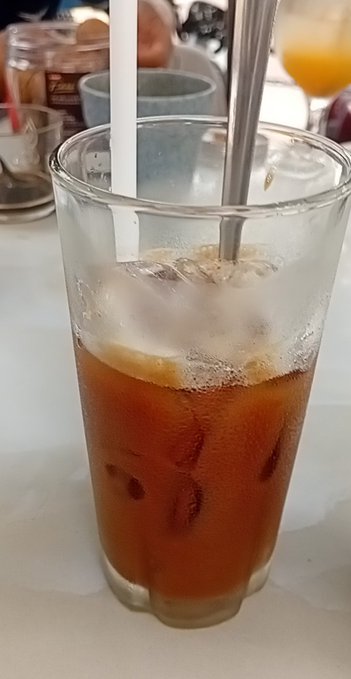 A glass of iced coffee or iced tea with a metal straw on a table.