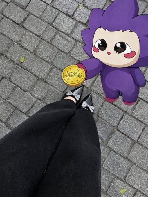 A person wearing black pants and pointed silver shoes, standing on a paved surface next to a cartoonish purple character holding a gold coin labeled "SCHOG".