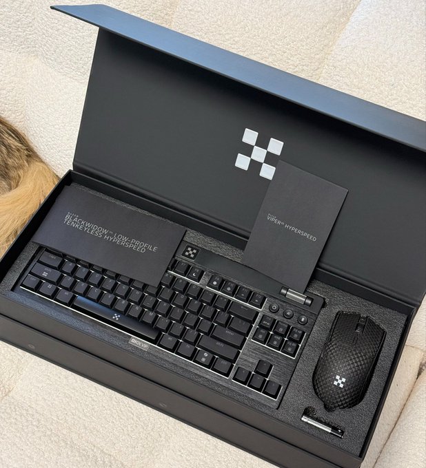 An OKX branded gift box containing a Razer BlackWidow V4 wireless keyboard and Viper V3 Hyperspeed mouse, with packaging text reading "BLACKWIDOW V4 LOW-PROFILE WIRELESS HYPERSPEED" and "VIPER HYPERSPEED" alongside the OKX checkered logo.