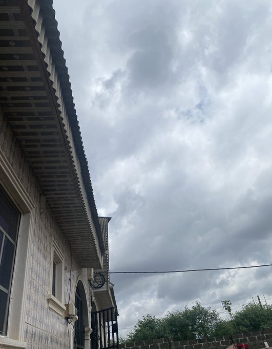 A low-angle outdoor photo of a building's ornate tiled facade and overhanging tiled roof against a cloudy gray sky.