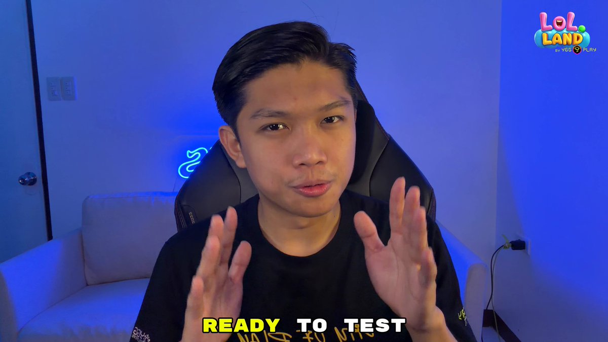 The image shows a man sitting down with his hands up, possibly preparing for an online test or game. The background features a blue wall that has neon signs hanging from it, adding a vibrant touch to the scene. There are also words visible on the image, such as " lol.land" and "focus on what is in the image".