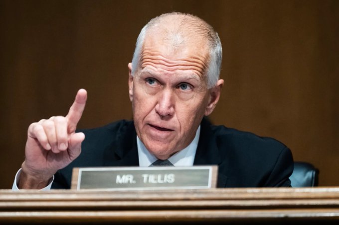 Senator Thom Tillis gestures while speaking at a hearing with a "MR. TILLIS" nameplate visible, illustrating the post's message that the White House and Senate may remain silent in the lead-up to a possible announcement.
