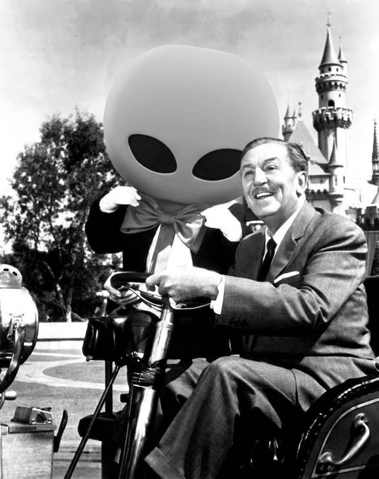 A vintage black-and-white photo shows Walt Disney smiling while sitting with the large-eared alien character from the Mickey Mouse Club, with a castle visible in the background.