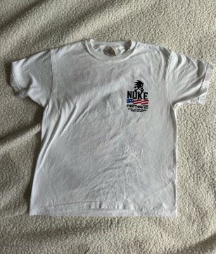 The image shows a white t-shirt laid out flat, with no other objects present. The t-shirt has a prominent "Nuke" logo in black text positioned at the top center of the shirt. The words "everything else" can also be seen on the front part of the shirt near the bottom edge.