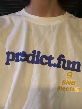 The image shows a person wearing a white T-shirt with "predict.fun" printed in blue across the front. The post describes wearing this merch at the Binance World Cup event, highlighting a surprise encounter with online contacts and valuable new connections—similar to past BNB meetups in Hong Kong.