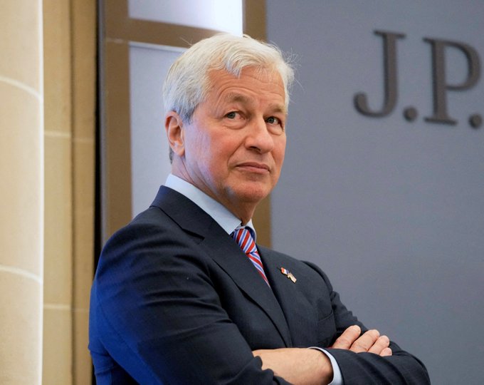 JPMorgan CEO Jamie Dimon stands with arms crossed in front of a "J.P." branded backdrop, as his firm significantly expanded its stake in BlackRock's Ethereum ETF from roughly 267,000 to 1.17 million shares in Q2.