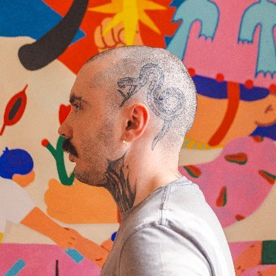 A profile shot of tattoo artist @narcisojuse, featuring intricate ink on the side of his shaved head and neck, set against a vibrant, colorful mural background. The image accompanies a Q&A post highlighting his upcoming meme card drop on 6529.io.