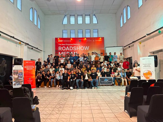 A group photo of attendees at a 'BYBIT INDONESIA ROADSHOW MEDAN' event, featuring The New Financial Platform banner and an ASUS logo.