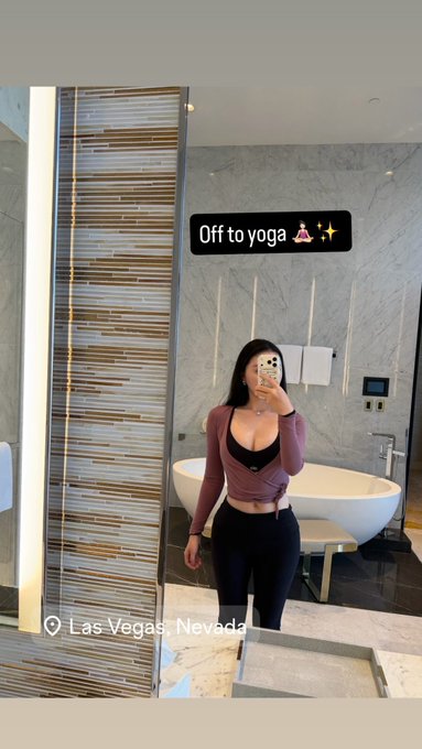 A mirror selfie of a young woman in a pink top and black leggings standing in a luxurious bathroom with a freestanding bathtub, captioned 'Off to yoga 🧘‍♀️✨' and tagged 'Las Vegas, Nevada'.