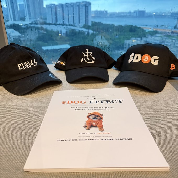 Three black $DOG-branded baseball caps sit behind a promotional pamphlet titled "THE $DOG EFFECT," which features a Shiba Inu in an orange hoodie and declares "$DOG the first memecoin native to Bitcoin, Incro Zero in the halving block" with a "FAIR LAUNCH, FIXED SUPPLY FOREVER ON BITCOIN" tagline, visually reinforcing the post's emphasis on $DOG's permanence and distinctiveness.