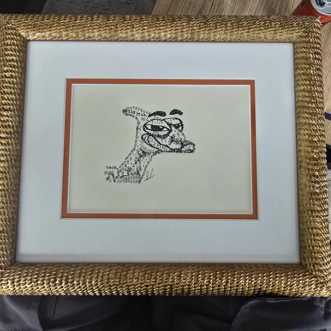 A framed pen-and-ink drawing of a woman's profile, composed of letters and small symbols, displayed in a woven wicker frame.