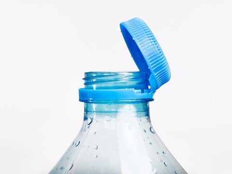 A close-up photograph of an open clear plastic water bottle with a blue flip-top cap against a white background.