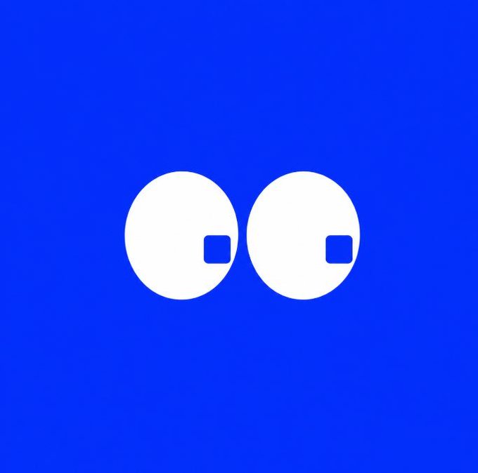 A simple graphic of two white circles with small blue squares inside, resembling a minimalist face on a blue background.