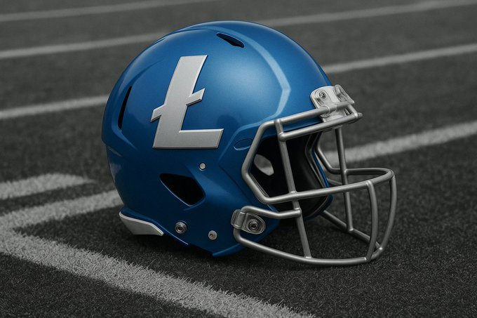 A blue American football helmet with a silver facemask and a white 'L' logo resting on a dark field with white yard lines.
