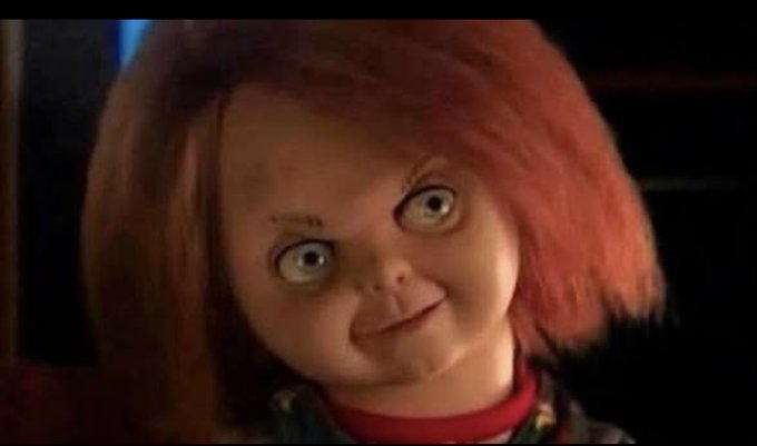 A still image of the iconic Chucky doll with red hair and freckles from the horror film Child's Play.
