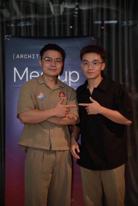 Two young men pose together at the Arc Meetup in Ho Chi Minh City, both pointing toward each other, standing in front of a banner displaying the "ARC" logo and "Meetup" text. The image captures the friendly, community-driven atmosphere of the event, reflecting the post's message of new connections and building the local Arc ecosystem.