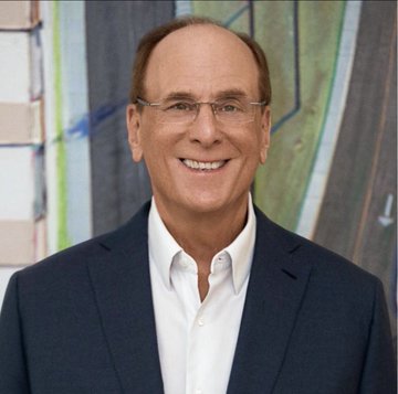 A professional headshot of a smiling middle-aged man wearing glasses and a dark blue blazer over a white collared shirt.