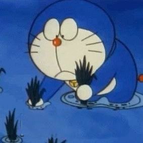 Doraemon, the blue cartoon cat character, appears to be pulling weeds or grass from water.