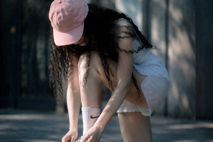 The image features a woman with long hair wearing a pink hat, who is bending over to tie her shoes. The photo has been edited to include text that reads "Nhiều người: đăng 1 bài check vài phút thấy ít tim rồi biến mạm trong khi những account tăng mạm là những người rep không ngừng nghỉ". The image is related to the post because it features a woman wearing a pink hat, which could be associated with the post's content.

The photo also includes text that reads "Nhiều người: đăng 1 bài check vài phút thấy ít tim rồi biến mạm trong khi những account tăng mạm là những người rep không ngừng nghỉ". This text is likely related to the editing process that was applied to the image.