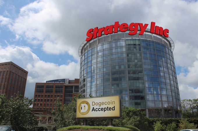 The image features a large building with a red sign that reads "Strategy Inc." above it, which is located next to a street. The sky has some clouds, but there are no people or other objects visible in the scene. There's also an additional sign on the side of the building that says "DOGE coin accepted". This suggests that the building might be related to cryptocurrency or digital assets, possibly serving as a hub for such businesses.