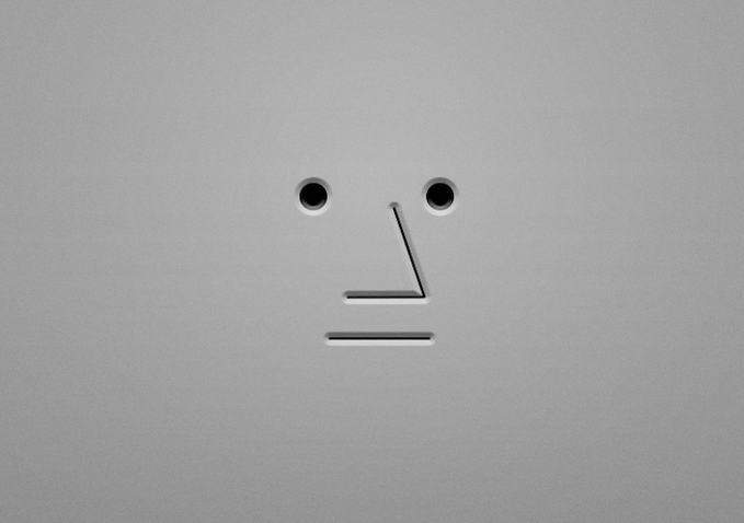 A minimalist image showing a small rectangular opening resembling a mouth and two small holes resembling eyes on a light gray textured surface.