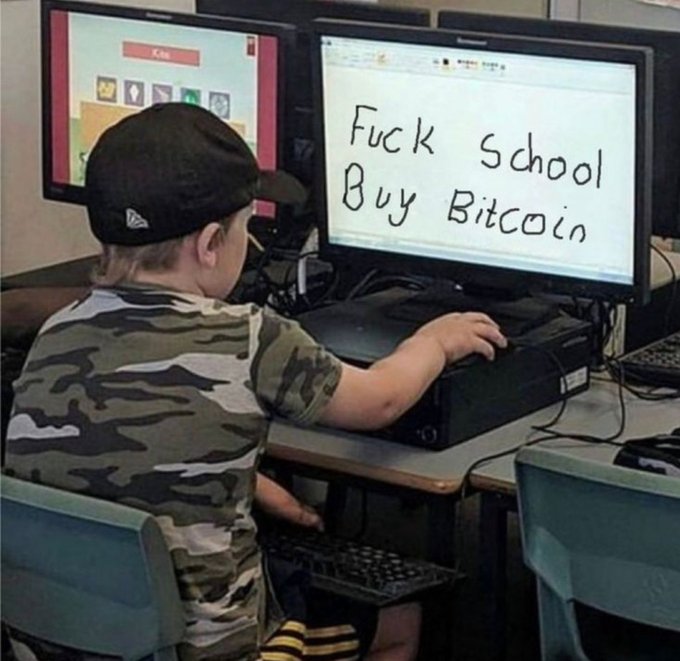A young child wearing a backwards cap and camouflage shirt sits at a computer with the handwritten message "Fuck School Buy Bitcoin" displayed on the monitor, humorously illustrating the viral "good or bad advice" dilemma.
