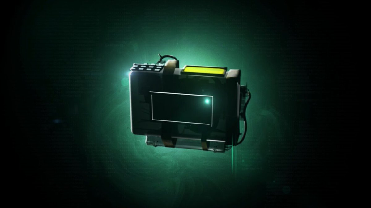 The image features a small electronic device, possibly an electronic device or a gadget, placed against a dark background with a green glow coming from above. The device appears to be a small computer monitor or TV screen that has been integrated into a larger object, such as a bag or a case. The device is positioned in the center of the image and seems to be the main focus.