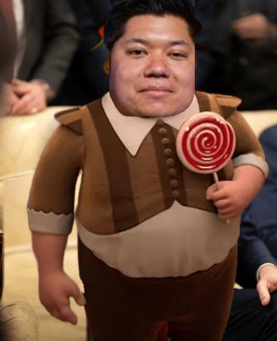 A digitally edited image showing a man's face superimposed onto a cartoon character's body holding a red swirled lollipop.