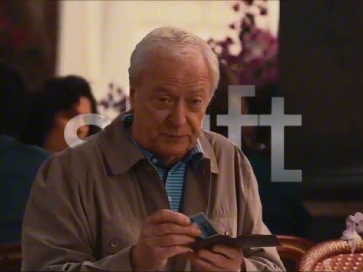 The image shows an older man sitting at a table, looking down at his wallet or purse while holding a credit card. The background reveals that he is in a restaurant setting with other people present around him. There are two chairs visible near the dining tables where the man is seated. A potted plant can be seen on one of the tables, and another person is sitting further back in the scene. The image also contains text related to a recent exploit called "Zcash exploit" that has caused privacy chaos for many users.