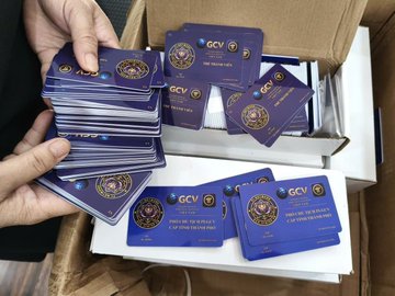 A person's hands hold stacks of purple business cards branded with "GCV" and "GLOBAL COMMUNITY OF VIETNAMESE ENTREPRENEURS," alongside loose cards and boxes, reflecting the post's call for pioneers to unite through legitimate channels like PurpleLotusGCV and the PiCoreTeam community.