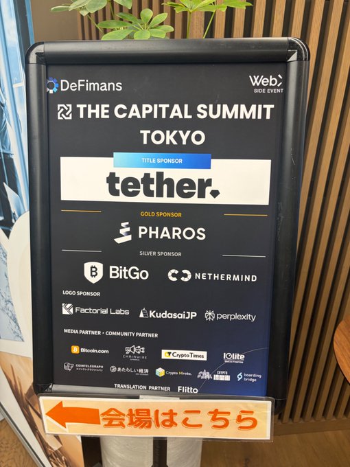 A photo of a sign for 'THE CAPITAL SUMMIT TOKYO' hosted by DeFimans, listing Tether as the title sponsor, Pharos as gold sponsor, and BitGo and Nethermind as silver sponsors, with a Japanese sign pointing to the venue.