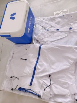 A white and blue insulated delivery bag with the 'M·MEIC' logo sits next to folded white raincoats or protective gear branded with 'MACK'.