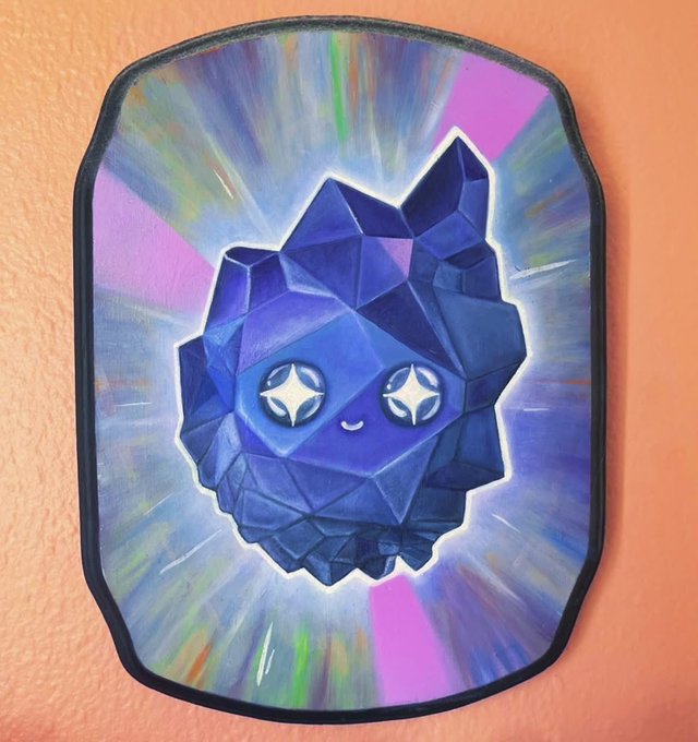 A colorful painting of a kawaii crystalline blue creature with star-shaped eyes, set against a radiating multicolored background on a shaped canvas.