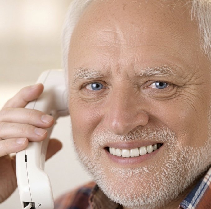 A close-up portrait of a smiling older man with white hair and a beard, holding a white telephone receiver to his ear.