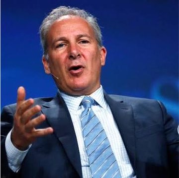 Photograph of a man in a blue suit and striped tie gesturing with his hand while speaking at an event, wearing a small earpiece microphone.