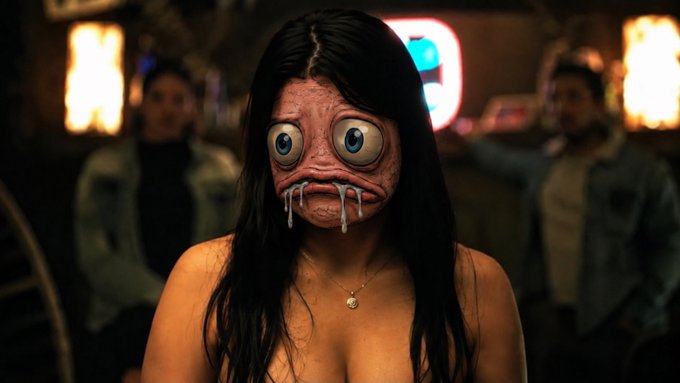 A creepy CGI figure with oversized blue eyes, pink skin, and needle-like teeth, resembling the Siren Head internet horror character, set in a dimly lit bar.