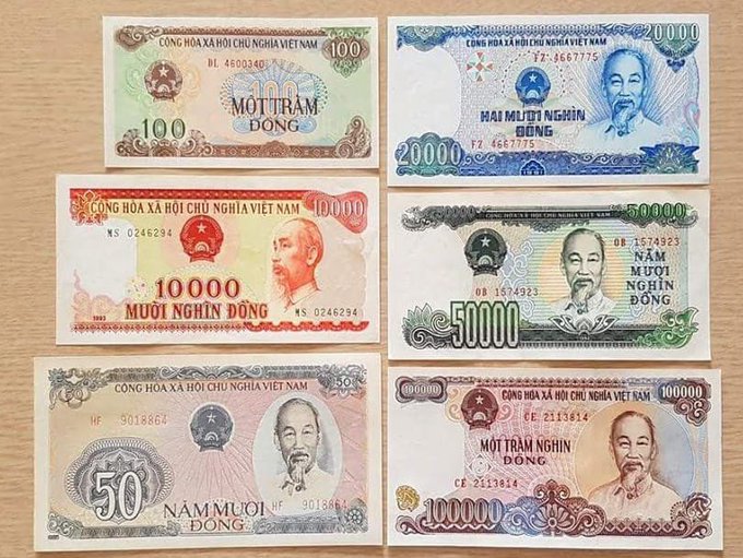 A collection of six Vietnamese Dong banknotes of various denominations (100, 20,000, 10,000, 50,000, 50, and 100,000) featuring Ho Chi Minh's portrait, laid out on a wooden surface.