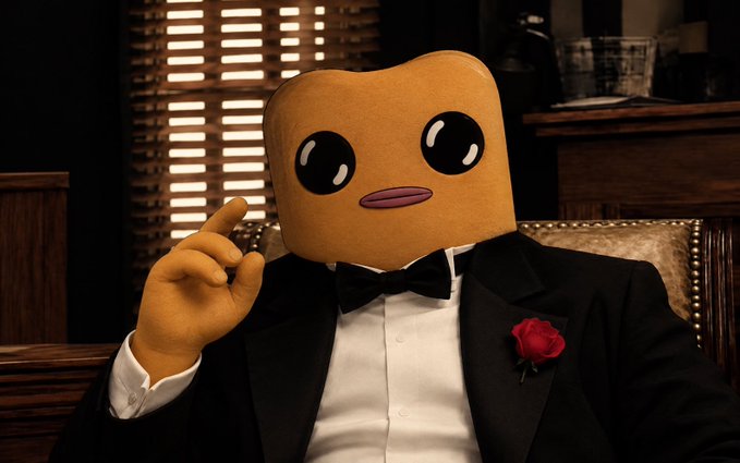 A character with a toast slice for a head and large black eyes sits at a desk wearing a black tuxedo with a bow tie and a red rose boutonnière, gesturing with its finger.