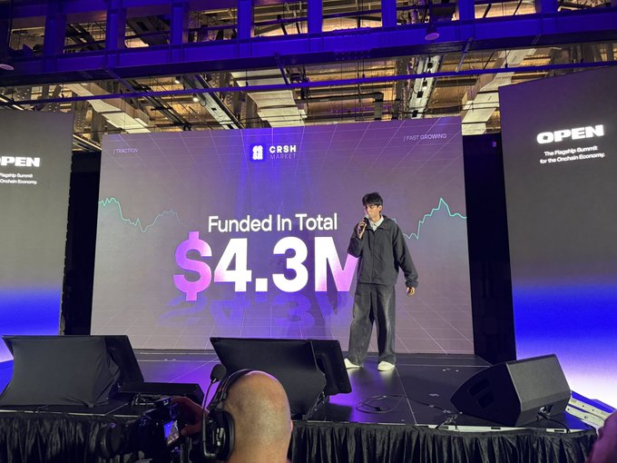 A presenter stands on stage in front of a large screen showing 'Funded In Total $4.3M' for the 'CRSH CAPITAL' track at an OPEN event.