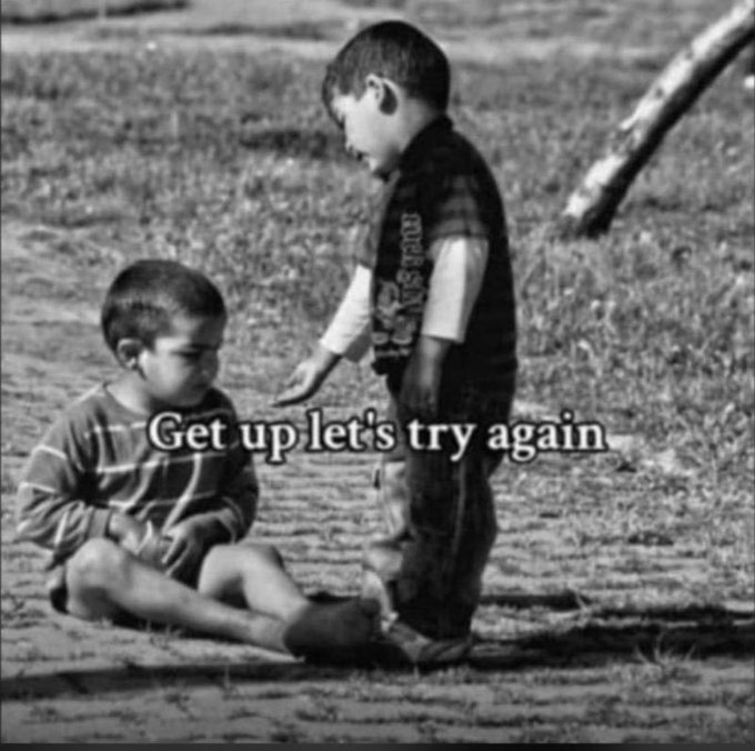 A black-and-white viral-style image of two young boys, with one sitting on the ground and another standing over him, featuring the inspirational caption 'Get up let's try again.'